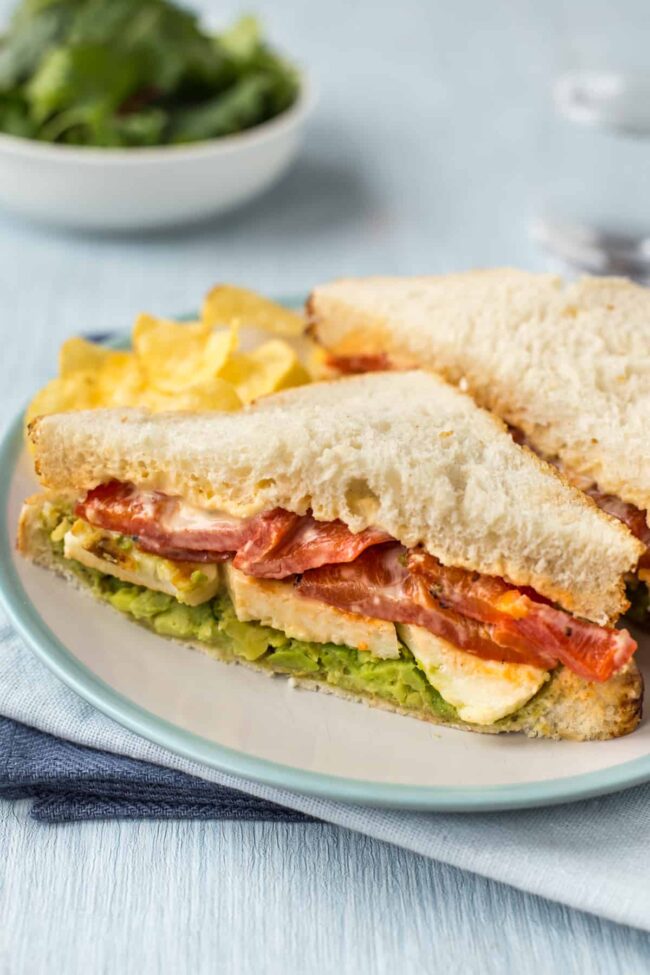 A sandwich filled with fried halloumi, roasted red peppers and mashed avocado.