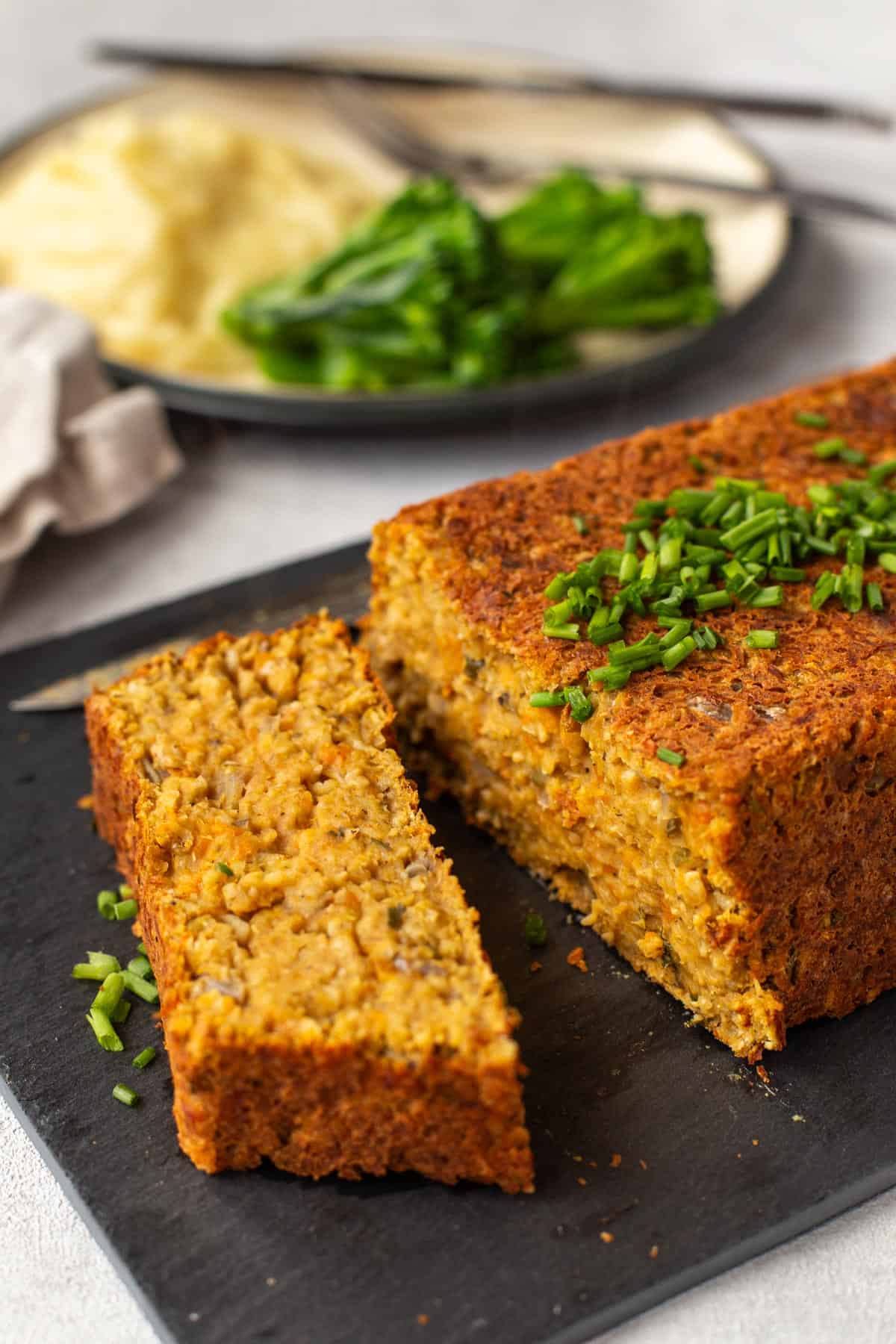 A slice cut from a vegan lentil loaf on a board.
