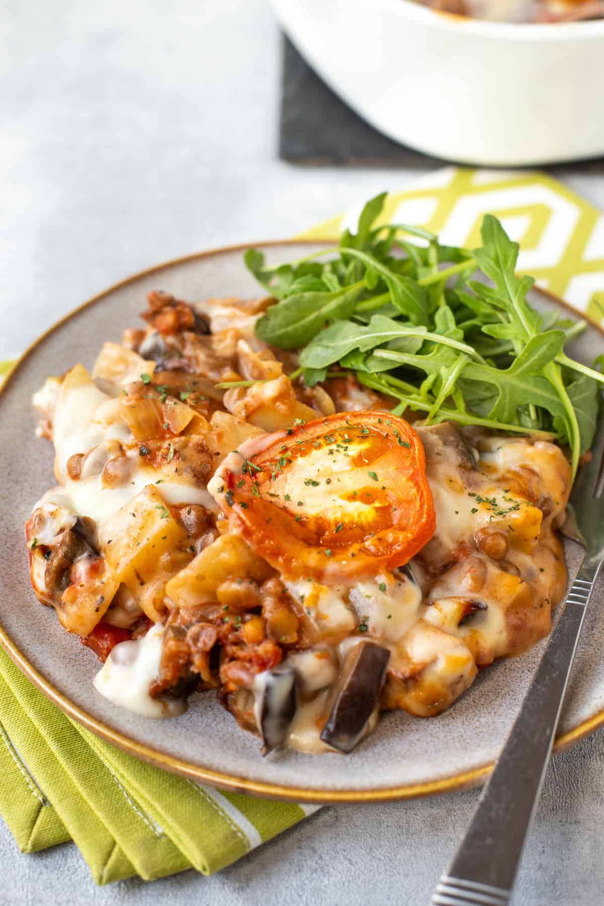 Vegetarian moussaka casserole topped with sliced tomato.