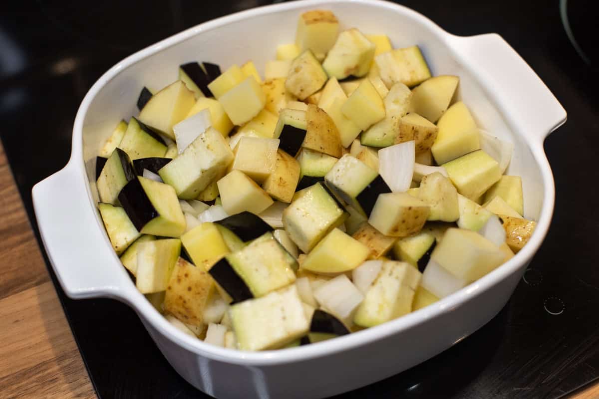 Diced potato, onion and eggplant in a baking dish.