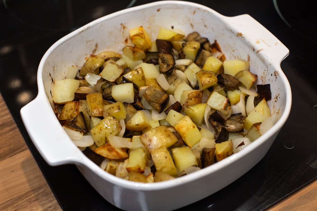Roasted potatoes, onion and eggplant in a baking dish.