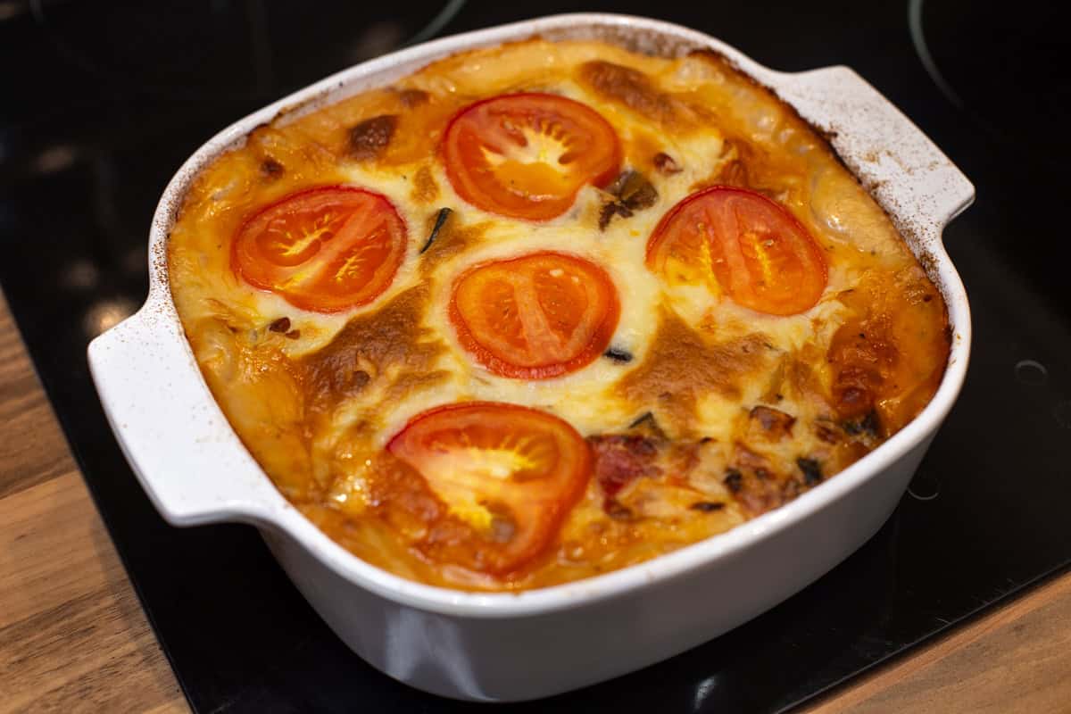 Cooked moussaka casserole topped with sliced tomatoes.