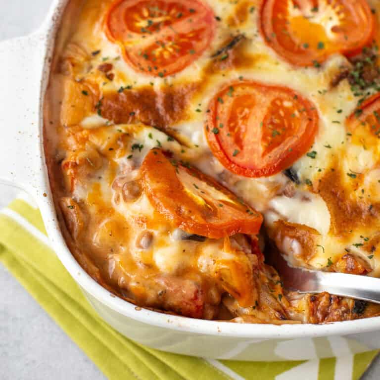 A large spoon taking a scoop of vegetable moussaka casserole.