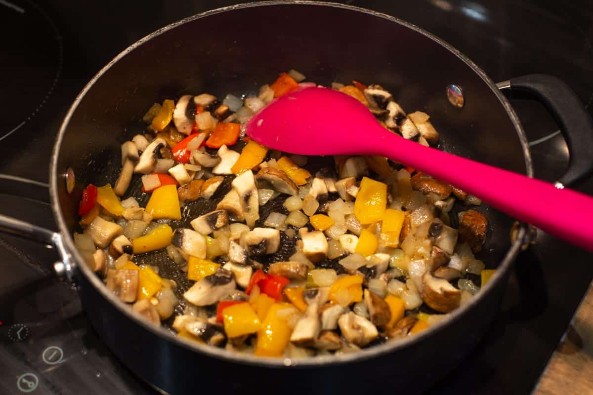 Mushrooms, onion and peppers cooking in a pan.