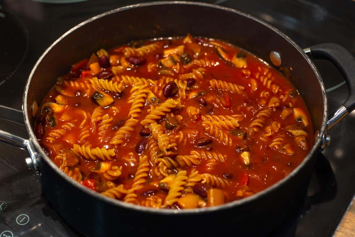 Partially cooked vegetarian chilli mac in a pan.
