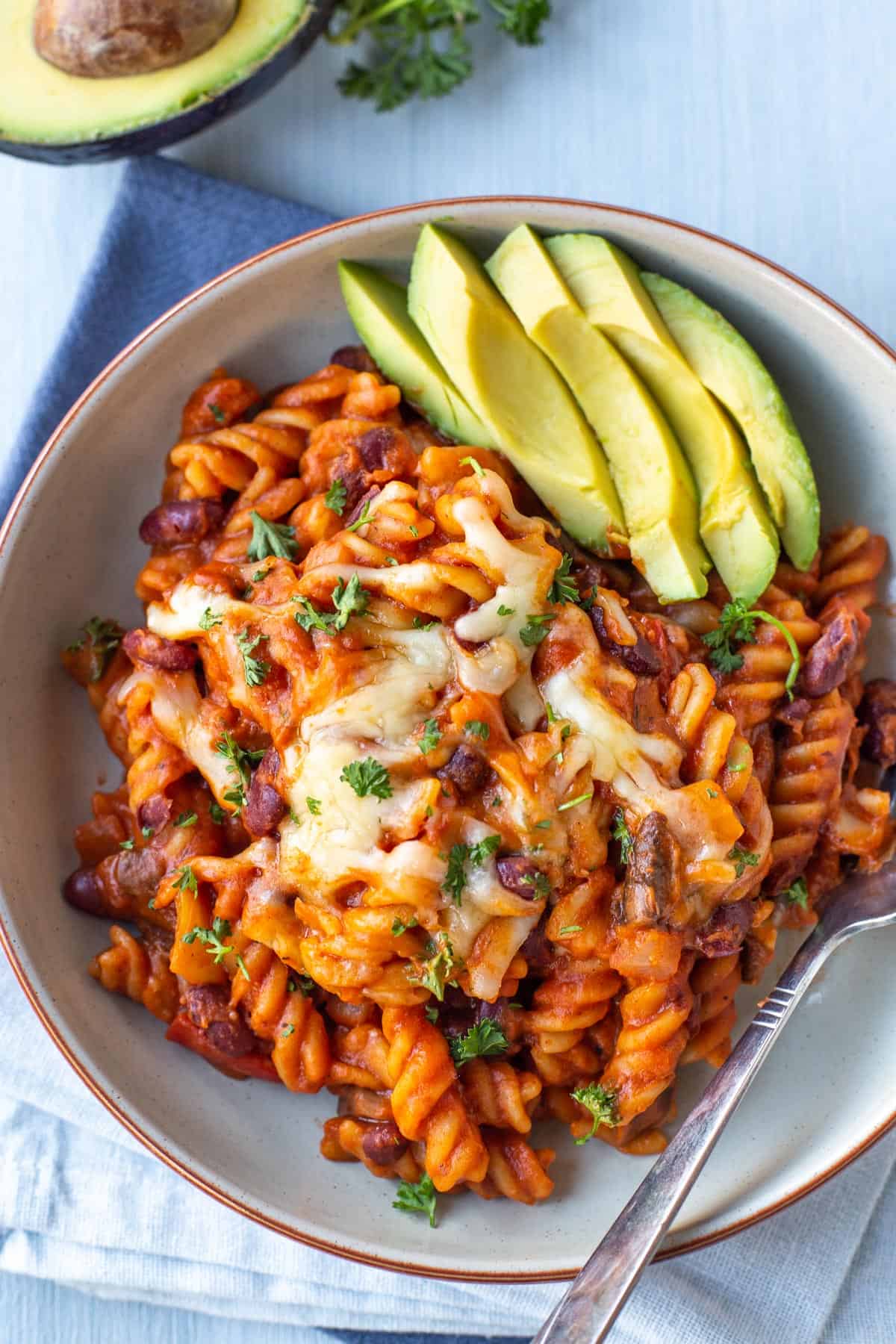 Cheesy vegetarian chilli mac with sliced avocado.