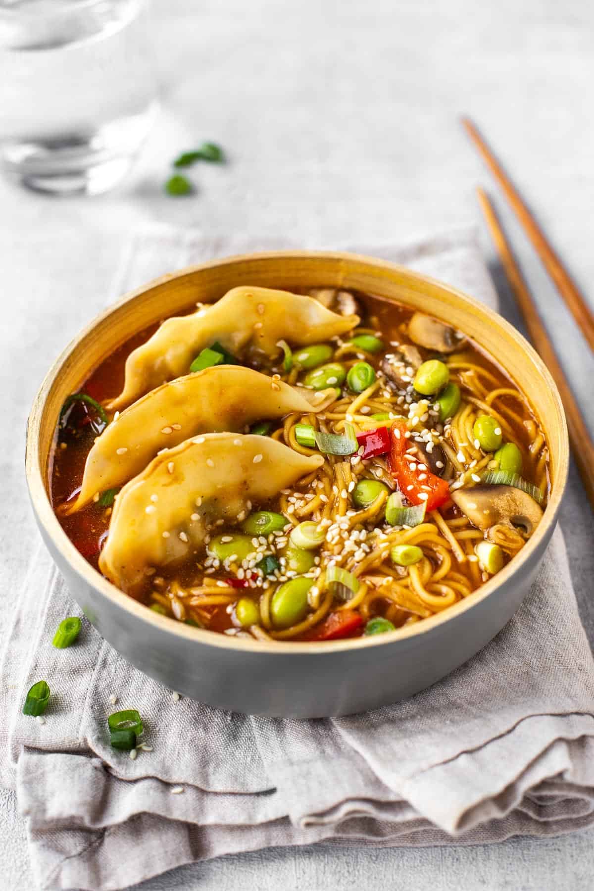 A bowlful of vegetarian gyoza soup topped with sesame seeds.