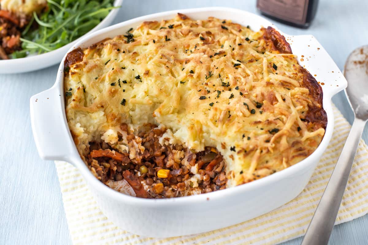 A baking dish of vegetarian shepherd's pie with a large scoop removed.