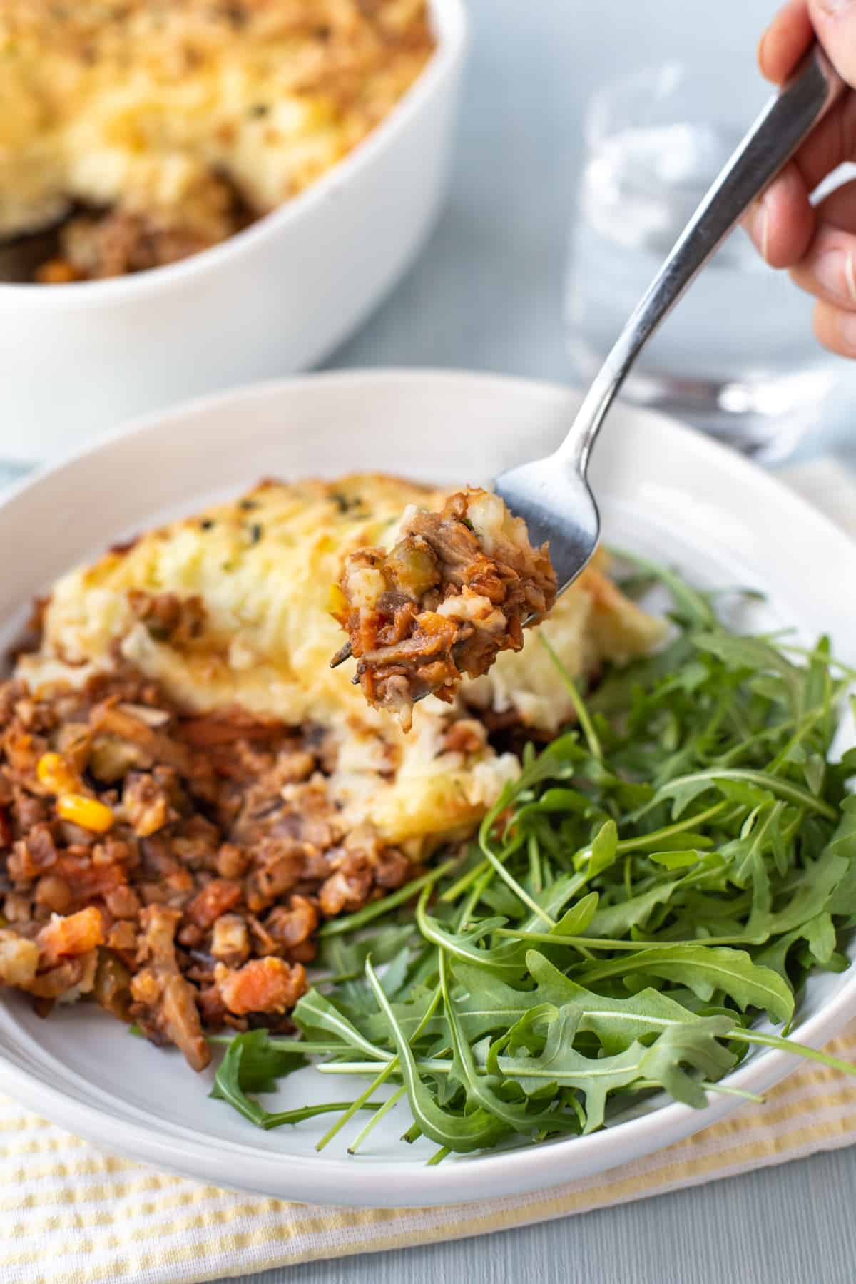 A fork holding up a scoop of vegetarian cottage pie.