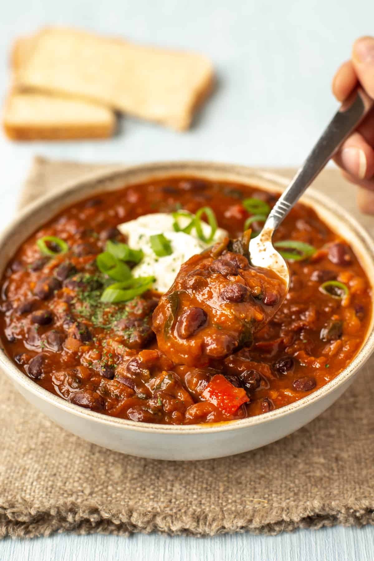 A spoon taking a scoop from a bowlful of black bean soup.