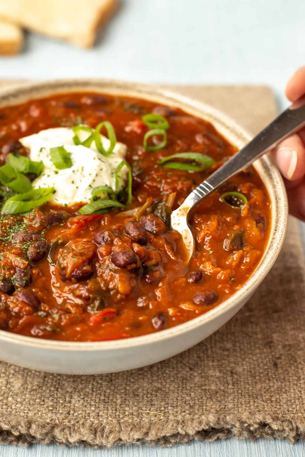 A spoon taking a scoop from a bowlful of black bean soup.
