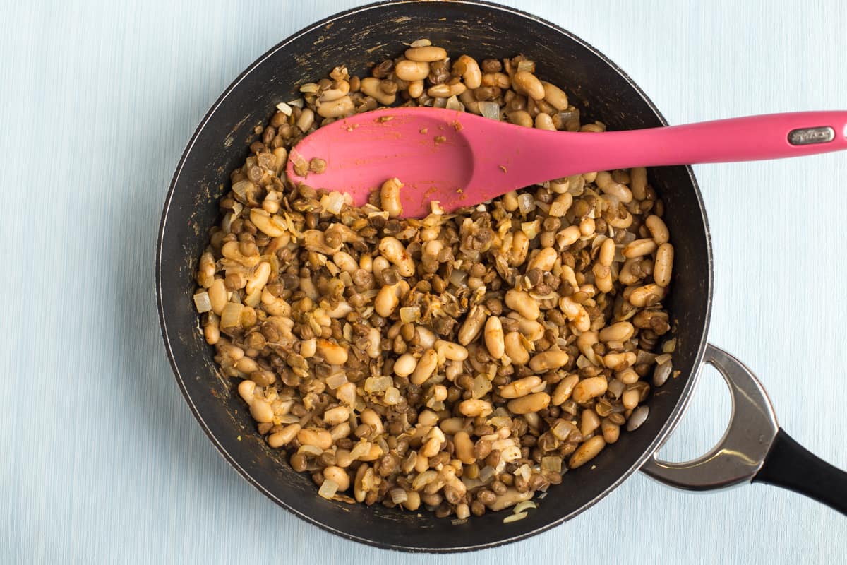 Beans and lentils cooking in a frying pan.