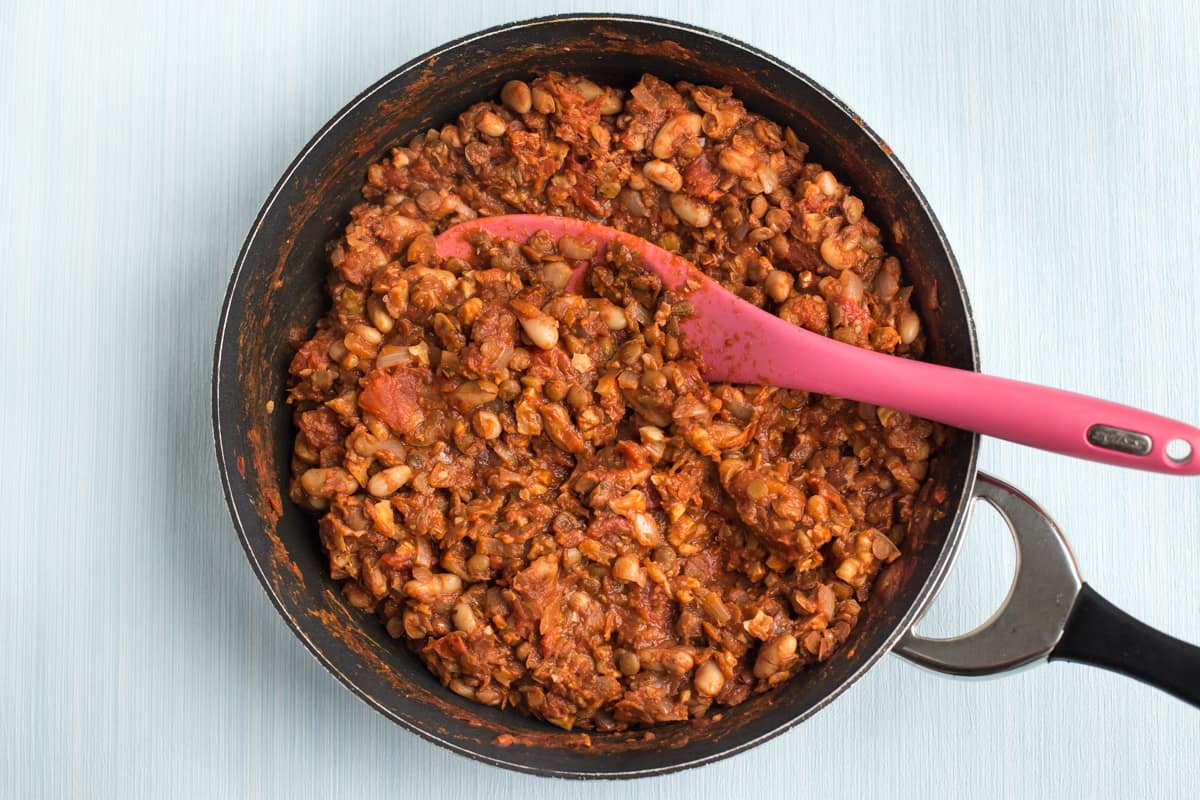 Rich tomato sauce in a frying pan with lentils and beans.