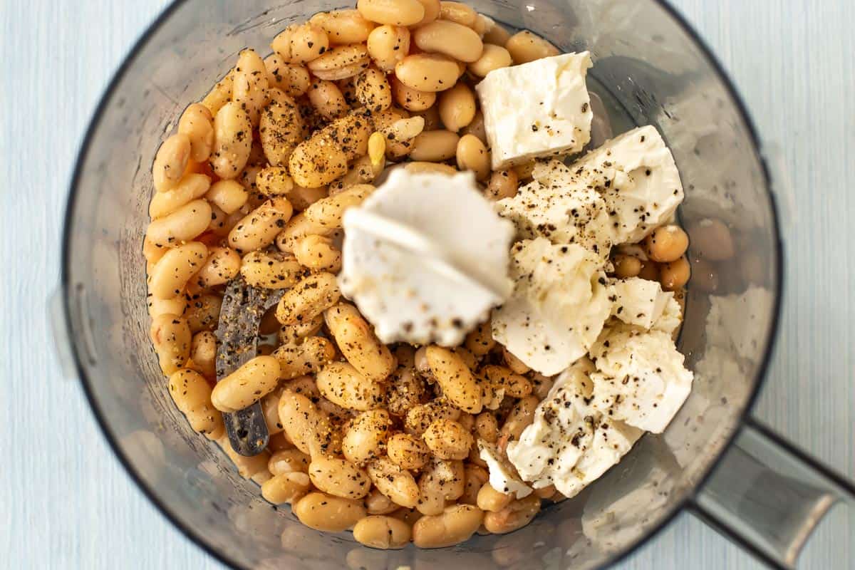 Ingredients for white bean and feta hummus in a food processor.
